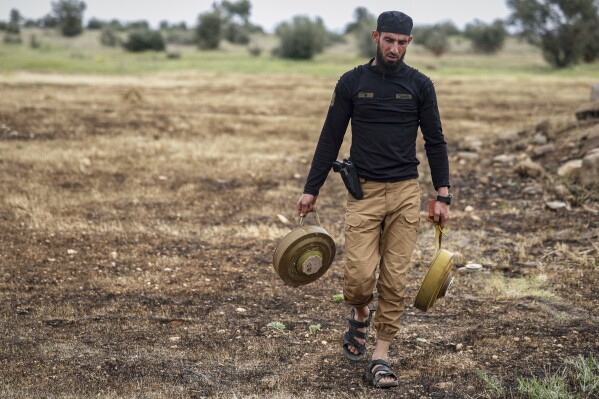 Members of the ministry of defence clear landmines left behind by the Syrian army during the war, in agricultural land south of Idlib, Syria, Sunday, April 13, 2025. (AP Photo/Ghaith Alsayed)