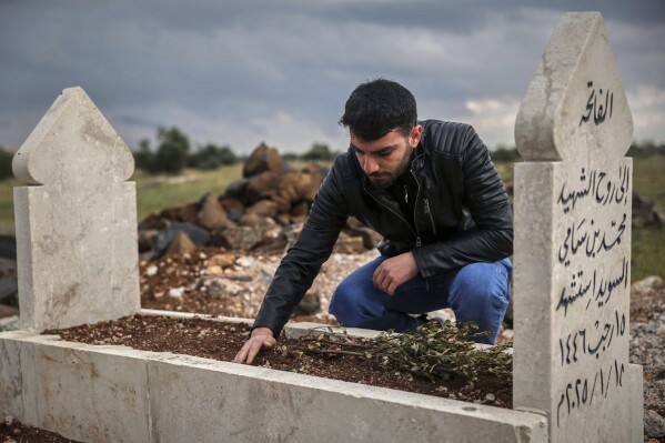 Salah Swed, 28, visits the grave of his brother Mohammed, who was killed while trying to dismantle a landmine, in their village of Kafr Nabl, south of Idlib, Syria, Monday, April 14, 2025. (AP Photo/Ghaith Alsayed)