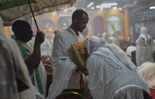 Worshippers kiss the holy Gospel during service at Re'ese Adbarat Debre Selam Kidist Mariam Church, an Ethiopian Orthodox Tewahedo church, in Washington, D.C., Saturday, April 5, 2025. (AP Photo/Jessie Wardarski)