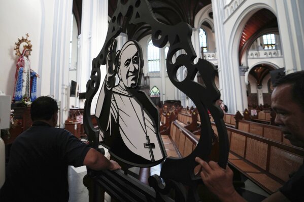 Church workers prepare an ornament depicting Pope Francis ahead of a mass at the Cathedral of Our Lady of the Assumption, which was visited by Pope Francis in 2024, in Jakarta, Indonesia, Monday, April 21, 2025. (AP Photo/Achmad Ibrahim)