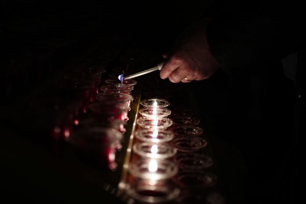 A person lights a candle at Liverpool Metropolitan Cathedral following the announcement by the Vatican of the death of Pope Francis aged 88, in Liverpool, England, Monday, April 21, 2025. (Peter Byrne/PA via AP)