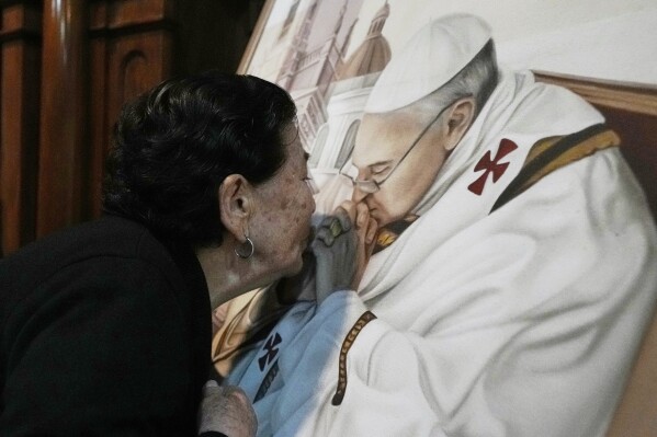 Genali Nogales kisses a painting of the late Pope Francis at the Basílica de San José de Flores, where he worshipped as a youth, following the Vatican's announcement of his death in Buenos Aires, Argentina, Monday, April 21, 2025. (AP Photo/Gustavo Garello)
