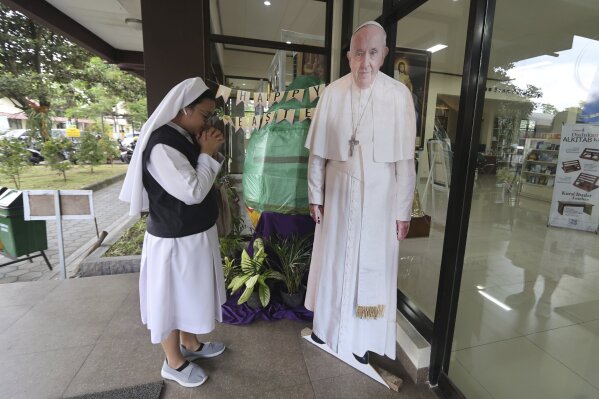 A Catholic nun prays in front of a cutout of Pope Francis in Yogyakarta, Indonesia, Monday, April 21, 2025. (AP Photo/Slamet Riyadi)