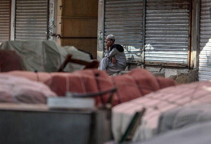 A labourer speaking on his mobile phone sits outside the closed shops to show their solidarity with Palestinians, in Karachi on April 26, 2025, amid the ongoing Gaza conflict. Photo: AFP