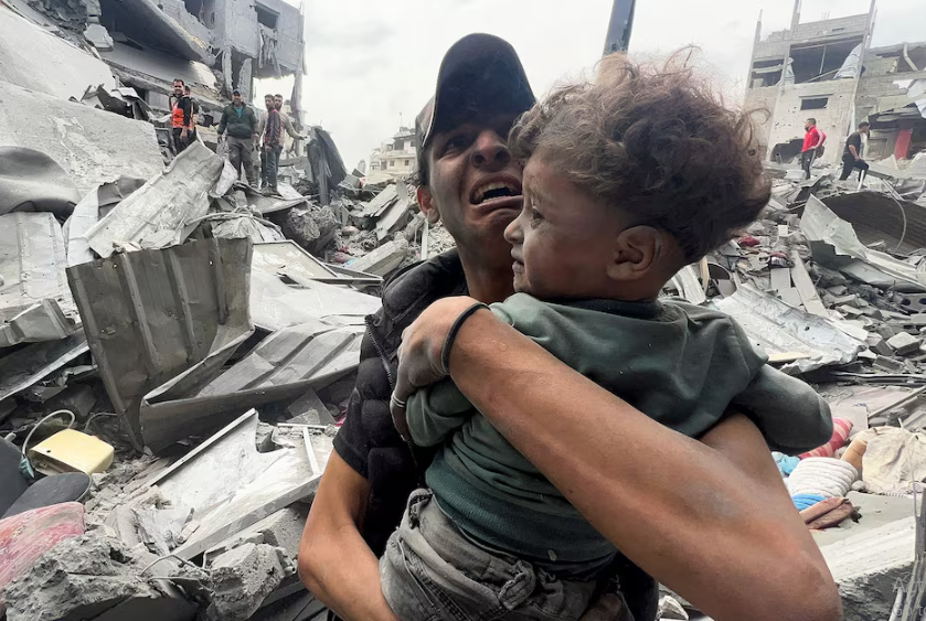 A Palestinian man reacts as he holds a child at the site of an Israeli strike on a house in Shejaia in Gaza City. PHOTO: REUTERS