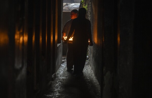 Nepalese vendors carry new butter lamps to sell to devotees during Buddha Jayanti or Buddha Purnima festival in Boudhanath Stupa, Kathmandu, Nepal, Monday, May 12, 2025. (AP Photo/Niranjan Shrestha)