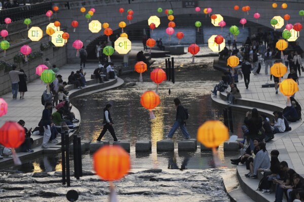 Visitors cross Cheonggye stream near the lanterns hanging to celebrate Buddha's upcoming birthday, in Seoul, South Korea, Friday, April 18, 2025. (AP Photo/Lee Jin-man)