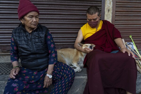 A Buddhist monk pets a stray dog on his lap during Buddha Jayanti, also known as Buddha Purnima festival, to celebrate Buddha's birthday, in Boudhanath Stupa, Kathmandu, Nepal, Monday, May 12, 2025. (AP Photo/Niranjan Shrestha)