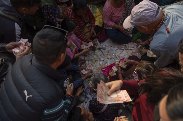 Nepalese devotees get their money changed to smaller denominations to offer them as alms to Buddhist monks during Buddha Jayanti, also known as Buddha Purnima festival, to celebrate Buddha's birthday, in Kathmandu, Nepal, Monday, May 12, 2025. (AP Photo/Niranjan Shrestha)