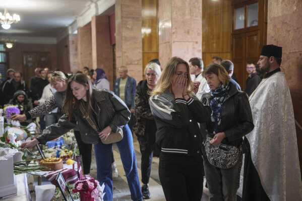 A woman cries during a funeral ceremony for Tamara Martyniuk, 8, Stanislav Martyniuk, 12, and Roman Martyniuk, 17, killed in a Russian strike on Sunday, in Korostyshiv, Zhytomyr region, Ukraine, Wednesday, May 28, 2025. (AP Photo/Evgeniy Maloletka)