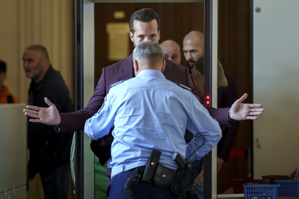 Tristan Tate, the brother of Andrew Tate, right, is checked upon arriving at the Court of Appeals building in Bucharest, Romania, Oct. 15, 2024. (AP Photo/Vadim Ghirda)
