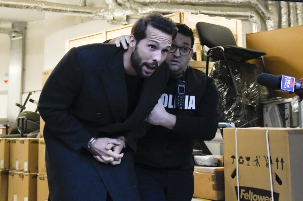 Tristan Tate, the brother of Andrew Tate is escorted from the Directorate for Investigating Organized Crime and Terrorism (DIICOT) after prosecutors examined electronic equipment confiscated during the investigation in their case, in Bucharest, Romania, Jan. 25, 2023. (AP Photo/Alexandru Dobre, File)