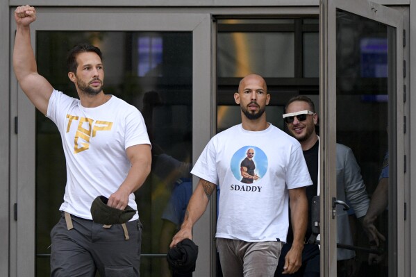 Andrew Tate, center, and his brother Tristan, left, exit the Bucharest Tribunal after being placed under house arrest, in Bucharest, Romania, Aug. 22, 2024. (AP Photo/Alexandru Dobre, File)