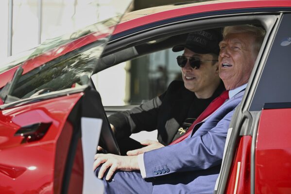 President Donald Trump and Tesla CEO Elon Musk speak to reporters as they sit in a red Model S Tesla vehicle on the South Lawn of the White House, March 11, 2025, in Washington. (Pool via AP, File)
