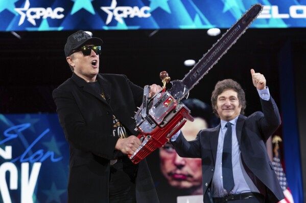Elon Musk holds up a chainsaw he received from Argentina's President Javier Milei, right, as they arrive to speak at the Conservative Political Action Conference, CPAC, at the Gaylord National Resort & Convention Center, Feb. 20, 2025, in Oxon Hill, Md. (AP Photo/Jose Luis Magana, File)
