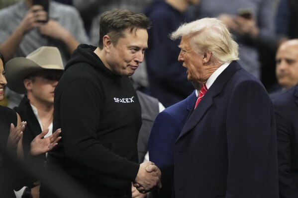 Elon Musk, left, shakes hands with President Donald Trump at the finals for the NCAA wrestling championship, March 22, 2025, in Philadelphia. (AP Photo/Matt Rourke, File)